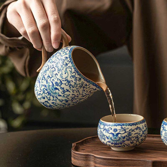 Ceramic teapot and cup with blue floral patterns being filled with tea on a wooden tray.